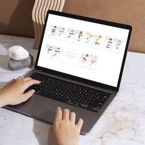 May include: A laptop computer with a white screen displaying a spreadsheet with colorful charts and graphs. The laptop is open and the keyboard is visible. The laptop is sitting on a white surface.
