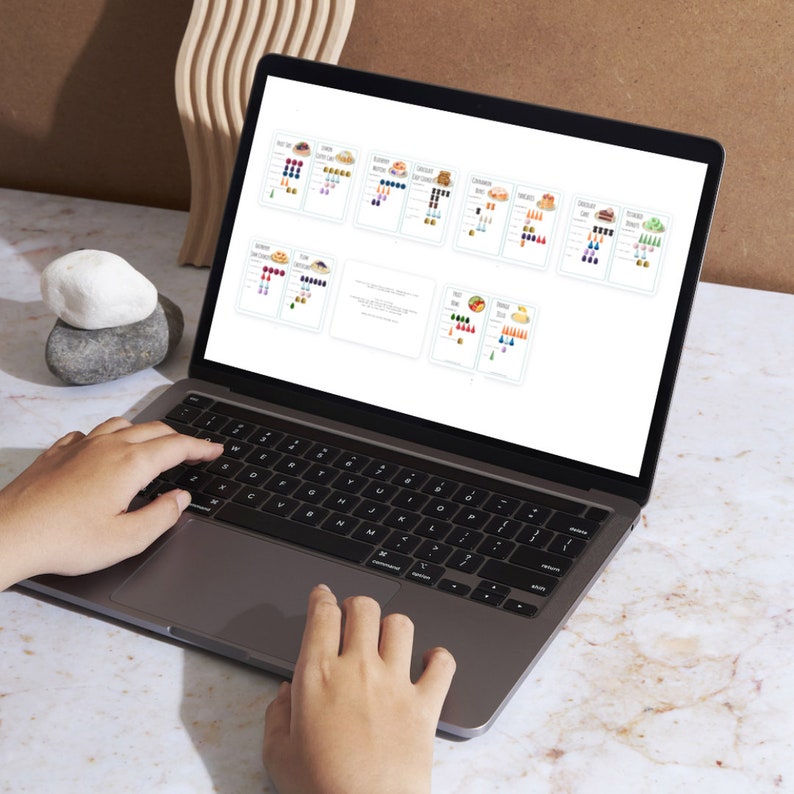 May include: A laptop computer with a white screen displaying a spreadsheet with colorful charts and graphs. The laptop is open and the keyboard is visible. The laptop is sitting on a white surface.