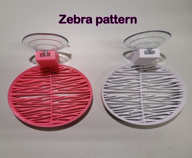 May include: Two suction cup holders with a zebra pattern. One is pink and the other is white.