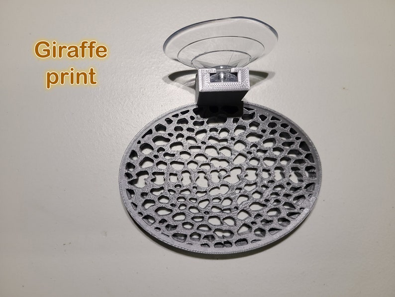 May include: A gray 3D printed suction cup holder with a circular, patterned design. The text "Giraffe print" is visible in the image.