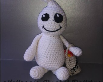 Puede incluir: Un fantasma blanco de crochet que sostiene una pequeña bolsa marrón con la palabra "Spook" en ella. El fantasma tiene ojos negros y una boca sonriente.