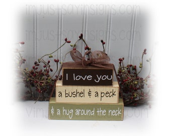 May include: Three wooden blocks stacked on top of each other. The top block is brown and says "I love you". The middle block is beige and says "a bushel & a peck". The bottom block is green and says "& a hug around the neck".