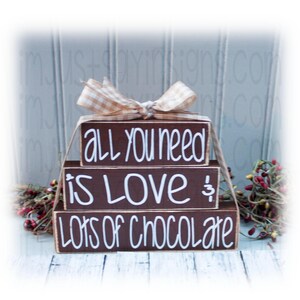May include: Stacked wooden blocks with the phrase "All you need is love & lots of chocolate" written in white paint.