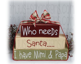May include: A three-tiered wooden block sign with a red, cream, and green color scheme. The top block reads "Who needs Santa..." in white lettering. The middle block reads "Santa..." in red lettering. The bottom block reads "I have Mimi & Papa" in white lettering.