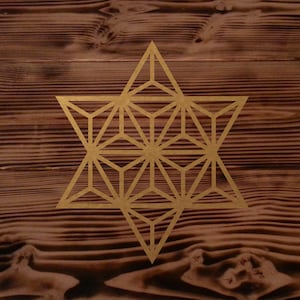 Può includere: Una stella geometrica dorata con dettagli intricati, su uno sfondo di legno marrone.