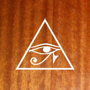 May include: A white outline of an eye inside a triangle on a brown wooden surface.