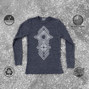 May include: A dark blue long-sleeved shirt with a white geometric design on the front. The shirt is made of organic cotton and is made in the USA.