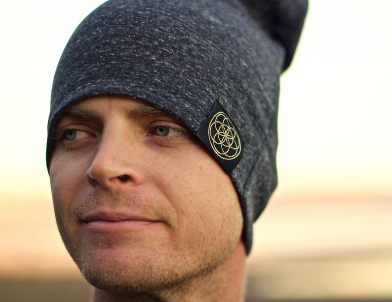 Puede incluir: Un gorro gris con un parche negro que presenta un dise&ntilde;o geom&eacute;trico dorado. El gorro est&aacute; hecho de un material suave y c&oacute;modo.
