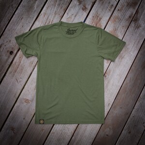 May include: A green t-shirt with a small logo that says "Sacred State" on the front.