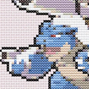 May include: Close-up of a cross-stitch design featuring a blue creature with white and black accents. The design is set against a light pink background, showcasing the detailed needlework and color variations.