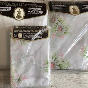 May include: Three Wondercale by Springmaid bed linen sets in plastic packaging. One set is white, the other has a floral pattern with pink and green accents. The packaging includes text such as "No-Iron Percale" and "Double Fitted".
