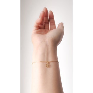 Peut inclure: Un bracelet délicat en chaîne dorée avec un petit charme en forme de fleur.