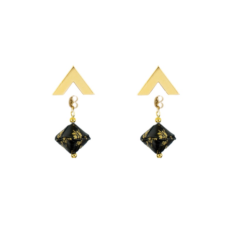 May include: A pair of gold earrings with black and gold geometric pendants. The earrings have a triangular top and a dangling geometric shape.