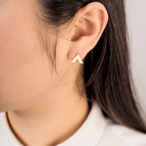 May include: A pair of gold triangle stud earrings. The earrings are small and simple, and they are a great way to add a touch of style to any outfit.