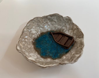 Handmade pottery jewelry bowl with boat in water