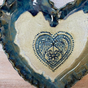 Puede incluir: Un plato de cer&aacute;mica en forma de coraz&oacute;n con un esmalte azul y un interior blanco. El plato tiene un dise&ntilde;o de coraz&oacute;n en relieve en el centro con un patr&oacute;n floral.