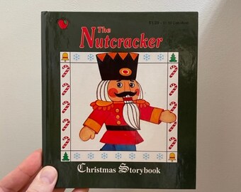 May include: A green book with a picture of a Nutcracker on the cover. The title is "The Nutcracker Christmas Storybook".