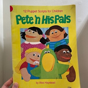May include: A yellow book with the title "Pete 'n His Pals" and the text "12 Puppet Scripts for Children". The book features a colorful illustration of five puppets, including a green bird, a girl with blonde hair, a girl with black hair, a boy with black hair, and a boy with brown skin.