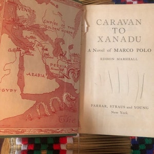 May include: A vintage book cover with a red and gold map of the Silk Road and the title "Caravan to Xanadu: A Novel of Marco Polo" by Edison Marshall. The book is published by Farrar, Straus and Young, New York.