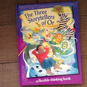 May include: A purple book titled "The Three Storytellers of Or" with a colorful illustration of a boy in bed, a zebra, and flowers. The book is labeled "a flexible-thinking book".
