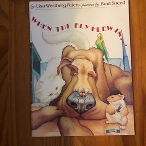May include: A children's book cover with a white cat, a brown dog, a green parakeet, and a hamster. The title of the book is "When the Fly Flew In."