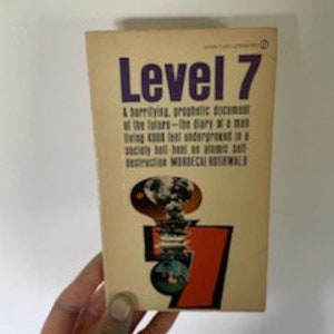 May include: A vintage paperback book titled "Level 7" with a yellow cover and a red and orange illustration of a globe with a lightning bolt. The book's subtitle is "A horrifying, prophetic document of the future - the diary of a man living 4000 feet underground in a society built on atomic self destruction." by Mordecai Roshwald.