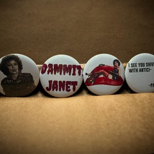 May include: Four white round buttons with images and text. One button features a woman with a cigarette, another reads "DAMMIT JANET" in red, a third shows a woman on red lips, and the last says "I SEE YOU SHIVER WITH ANTICI- -PATION."