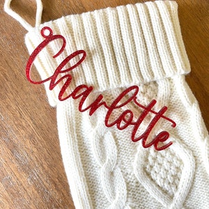 May include: White knitted Christmas stocking with a red glitter name tag that says "Charlotte".