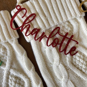 May include: White knitted Christmas stocking with a red glitter name tag that says "Charlotte".