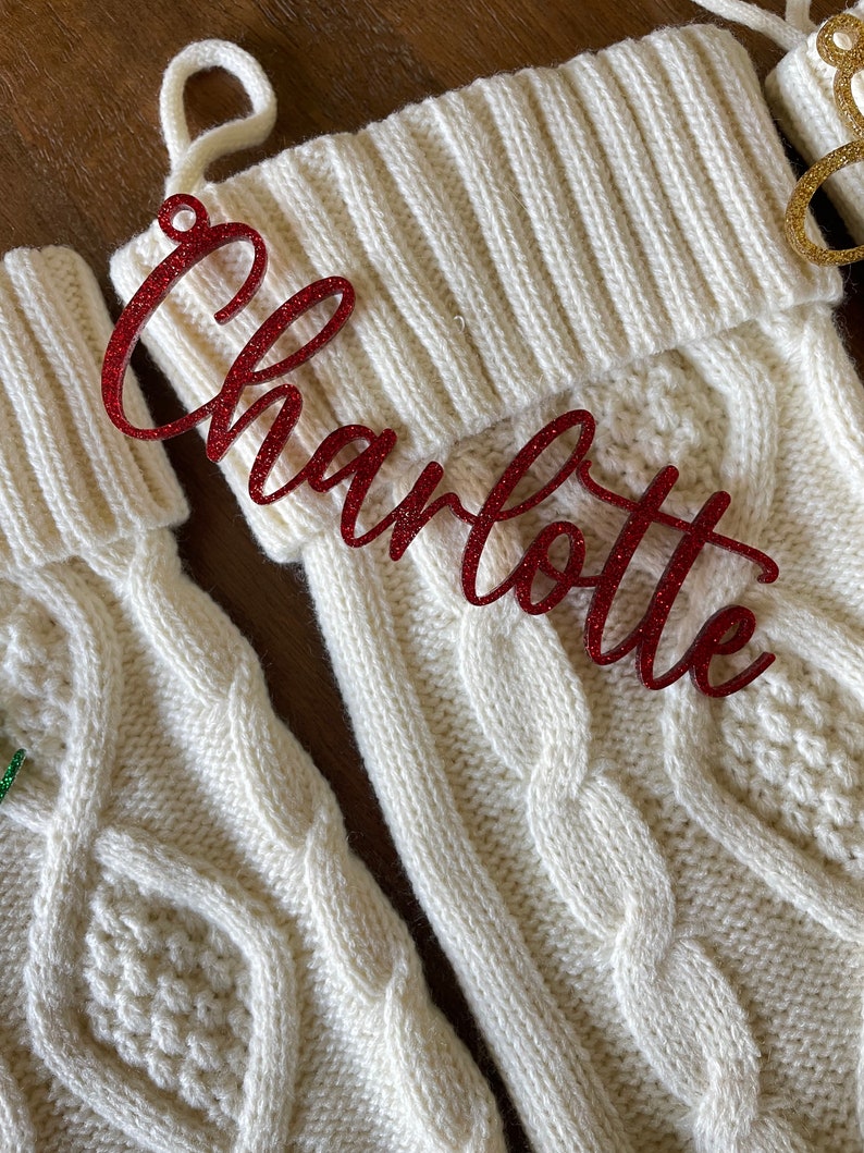 May include: White knitted Christmas stocking with a red glitter name tag that says "Charlotte".