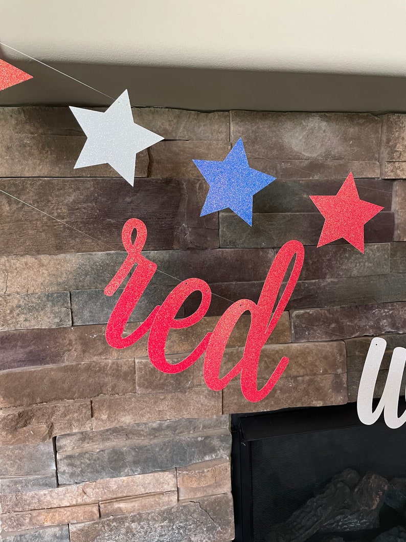 May include: A patriotic banner with red glitter text that reads "red" and white glitter text that reads "white". The banner also features glittery stars in red, white, and blue, perfect for a 4th of July celebration.