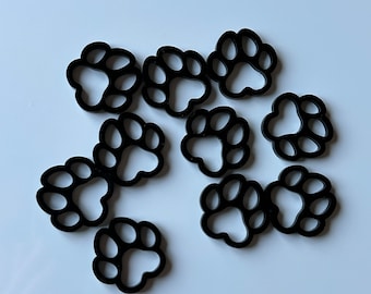 May include: Ten black plastic paw print charms. The charms are about 1 inch in diameter and have a smooth, glossy finish.