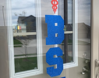 May include: A blue and red glitter door decoration with the letters "BSN" and a red glitter medical symbol.