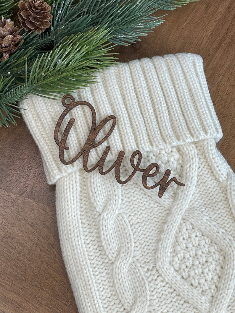 May include: A white knitted stocking with a wooden name tag that says "Oliver".