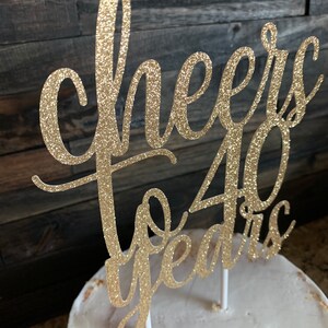 May include: Gold glitter cake topper with the text "Cheers to 40 years".