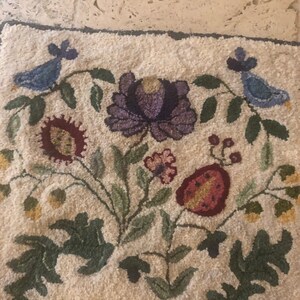 May include: A white rug with a floral design featuring purple, red, yellow, and green flowers. Two blue birds are on either side of the rug.