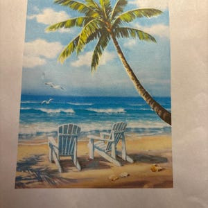 May include: A beach scene painting featuring a palm tree, two white Adirondack chairs, and seagulls flying over the ocean. The artwork depicts a sunny day with blue skies and waves. The painting is on a white background.