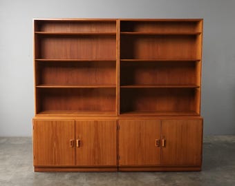 Könnte beinhalten: Zweiteiliges Bücherregal aus Holz in warmem, mittelbraunem Farbton. Der obere Teil hat offene Regale, der untere Teil Schranktüren. Ein klassisches Bücherregal zur Aufbewahrung von Büchern und Dekorationsartikeln.