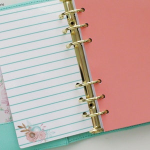 May include: Open planner with gold rings, featuring lined paper with teal stripes and floral accents. Coral-colored divider and a teal cover are visible. The planner includes a "TO DO" tab.