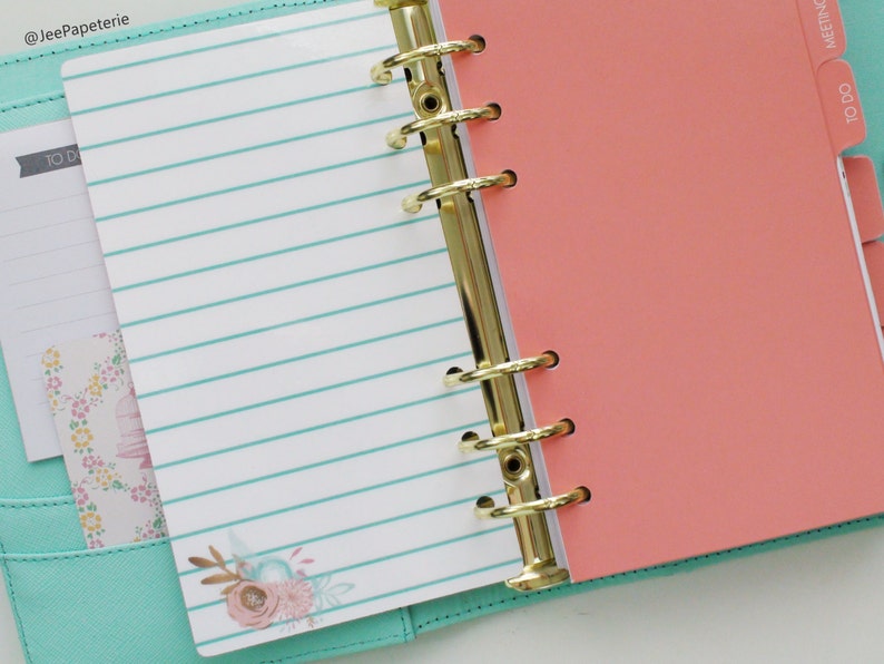 May include: Open planner with gold rings, featuring lined paper with teal stripes and floral accents. Coral-colored divider and a teal cover are visible. The planner includes a "TO DO" tab.