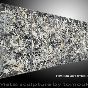 Può includere: Una scultura astratta in metallo nero, bianco e grigio con una superficie testurizzata. La scultura è composta da quattro pannelli.