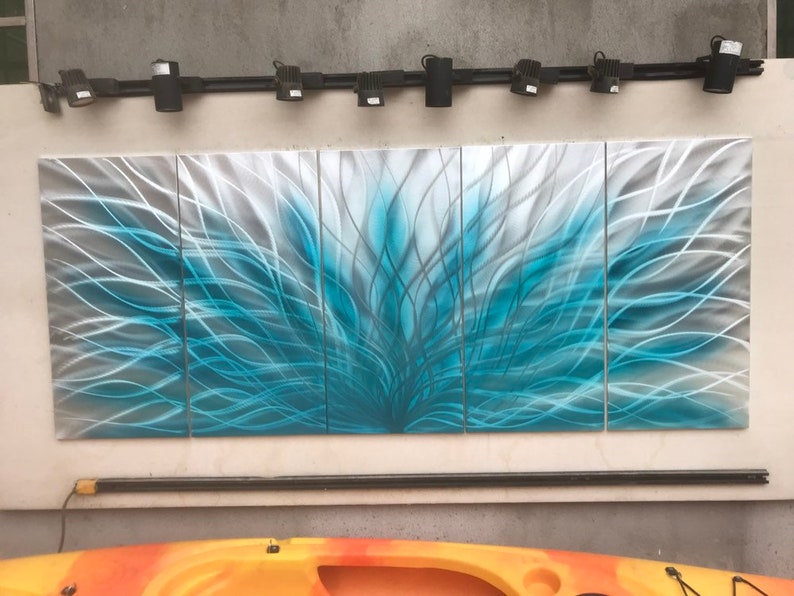 May include: A four-panel metal wall art piece with a blue and silver abstract design. The artwork features a swirling pattern of lines that create a sense of movement and energy.