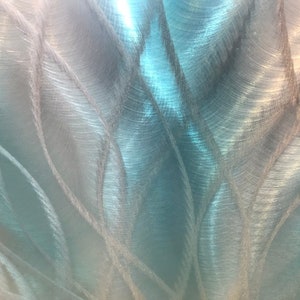May include: Abstract metallic background with a brushed silver and blue finish. The surface has a swirling pattern of lines and curves.