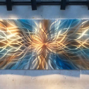 Può includere: Una scultura murale astratta in metallo in tre pezzi con un motivo a spirale di linee metalliche dorate e blu. La scultura è realizzata in metallo e ha uno stile moderno e contemporaneo.