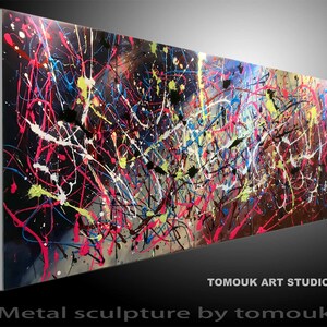Può includere: Scultura astratta in metallo con sfondo nero e schizzi di vernice colorati in tonalità di rosa, blu, giallo e bianco. La scultura è intitolata "Metal sculpture by tomouk" ed è firmata "Tomouk Art Studio".