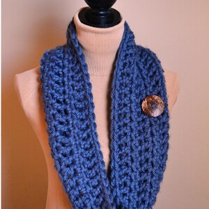May include: A blue crocheted cowl with a wooden button. The cowl is on a mannequin wearing a beige turtleneck. The text "Pure Grace Threads" and "{Carpe Diem Button Cowl Pattern}" is below the cowl.