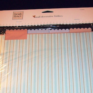 May include: A package of small decorative folders. The folders have a light blue and white striped pattern with gold vertical lines. The tabs are pink and scalloped. The package is labeled "heidi grace designs" and "small decorative folders."
