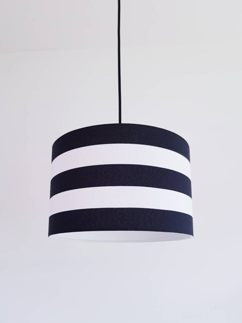May include: A black and white striped pendant light fixture with a cylindrical shade.