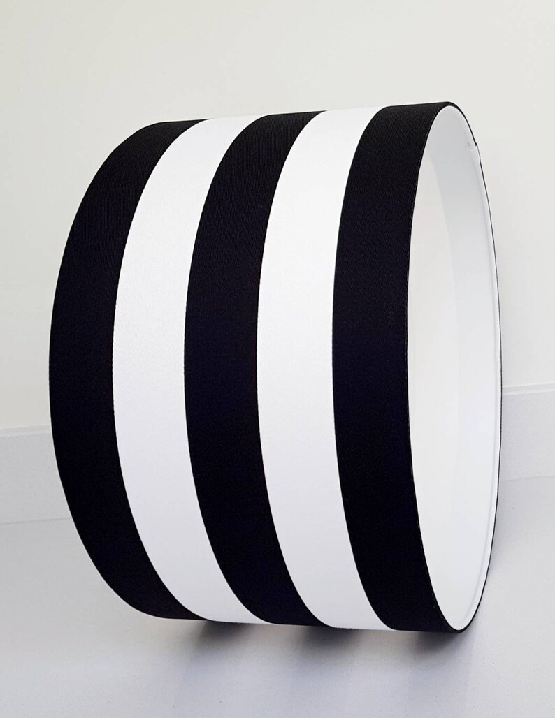 May include: Black and white striped lampshade with a cylindrical shape.