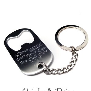 May include: A silver bottle opener keychain with the text "Some HEROES Don't Have Capes We Call Ours DAD". The keychain has a bottle opener on one end and a key ring on the other.